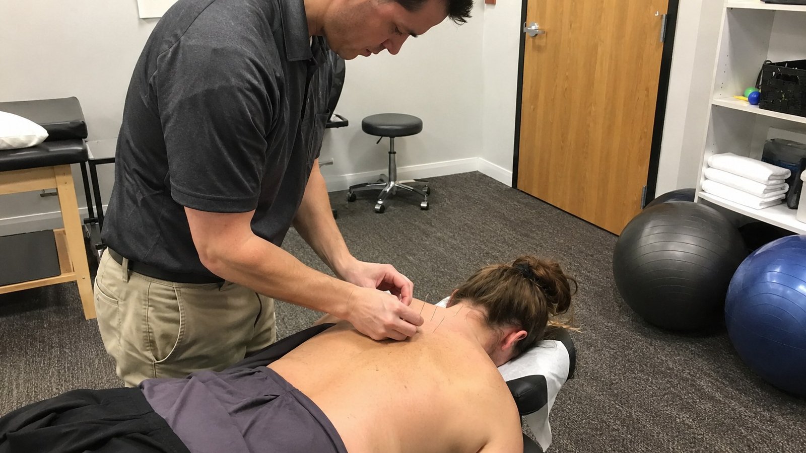 Practitioner performing dry needling on a patient’s upper back