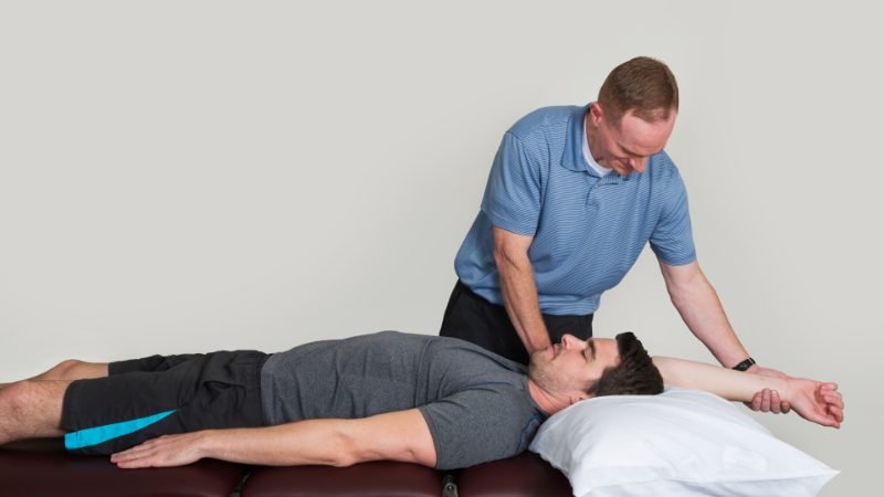 Therapist providing hands-on treatment while a patient lies on a treatment table