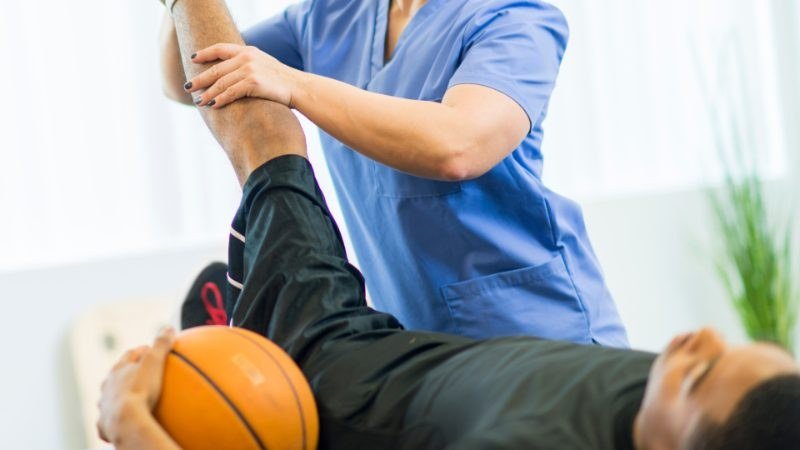 Therapist assisting an athlete with a leg mobility exercise